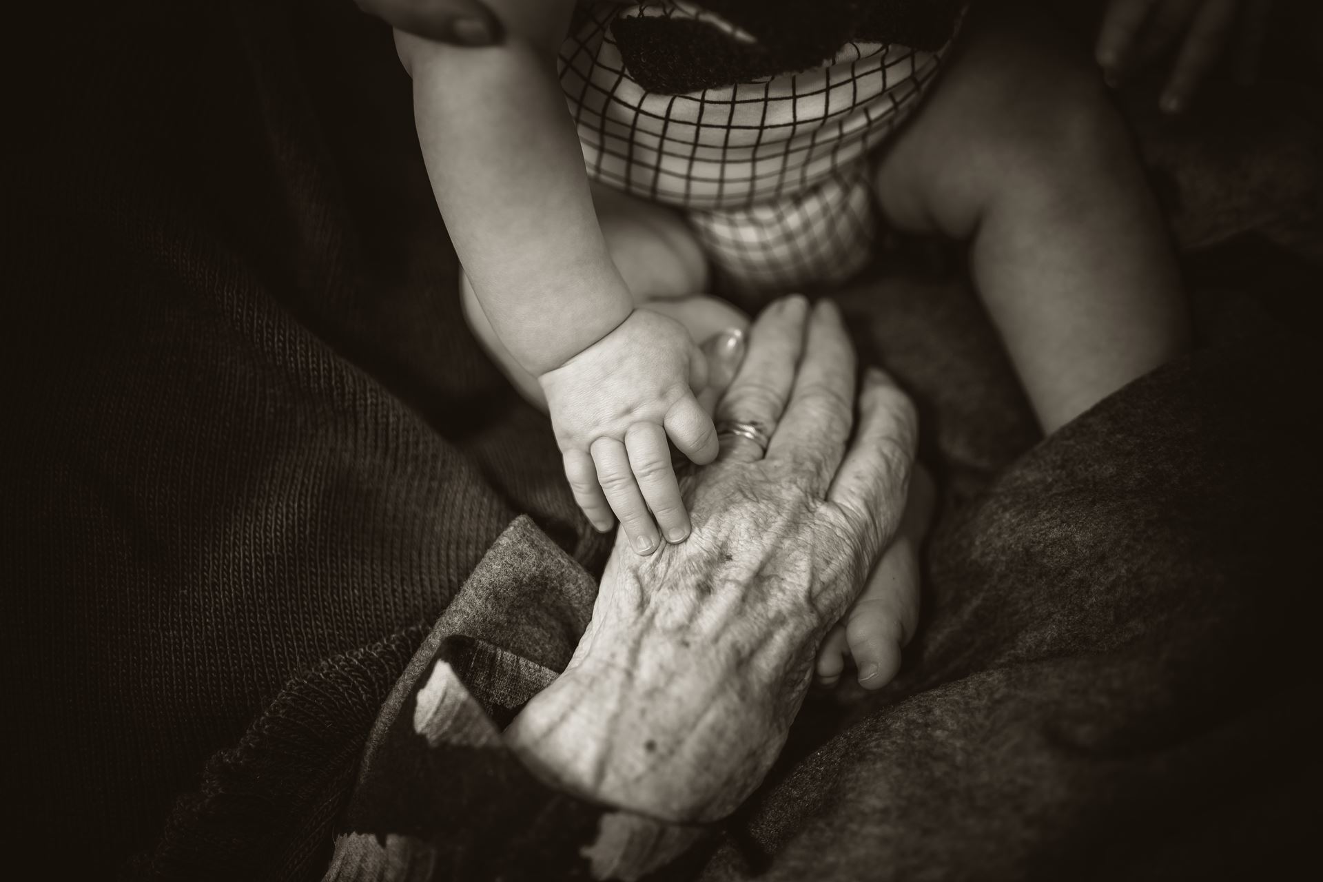 a baby and elderly person holding hands